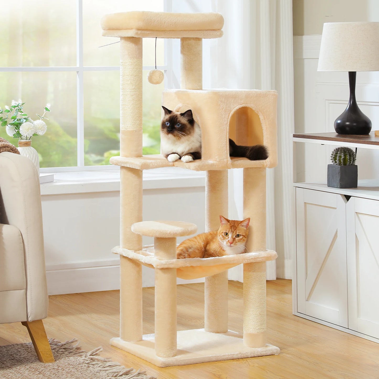 Cat tree with two cats in a room with a window and furniture.