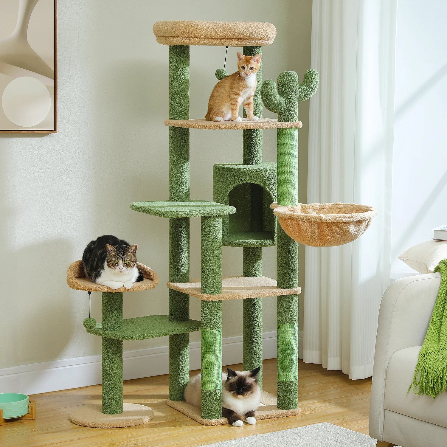 Green cat tree with multiple levels and a basket, featuring three cats in a room.